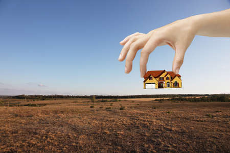 hand holding house and fieldの写真素材