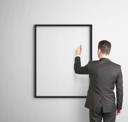 businessman drawing on black frames on wallの写真素材