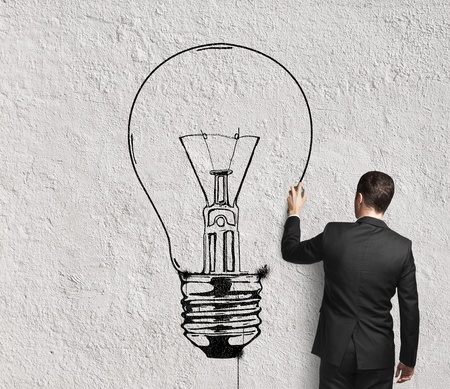 businessman drawing lamp on wallの写真素材