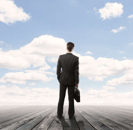 businessman standng on wooden floor and looking  blue skyの写真素材