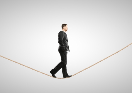 businessman walking on rope on a white backgroundの写真素材