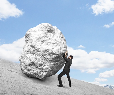 businessman pushing stone up hill and skyの写真素材