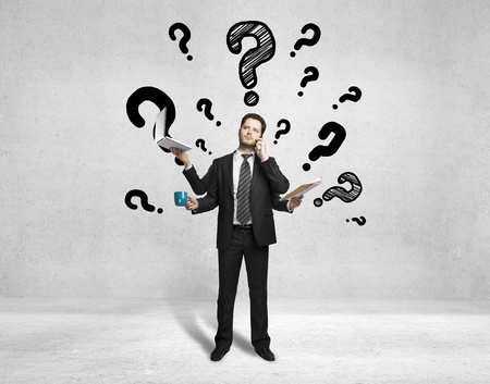 man with four hands holding various instruments and question marks over headの写真素材