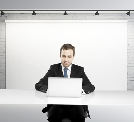 Businessman sitting at a table with a laptop in studioの写真素材