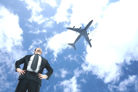 businessman looking on airplane in blue skyの写真素材