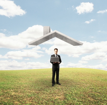businessman standing under house roof on nature backgroundの写真素材