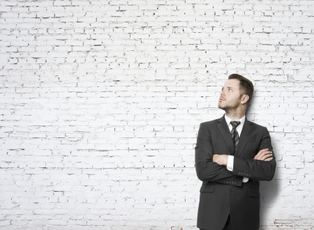 businessman leaning against a brick wall and thinkingの写真素材