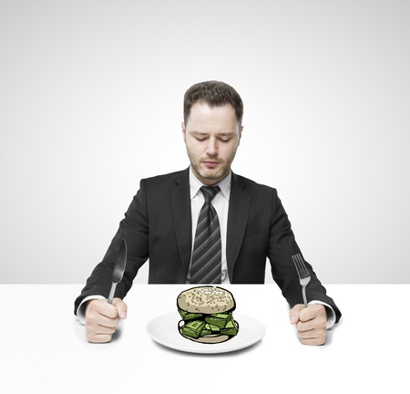 businessman sitting on table and eating hamburger moneyの写真素材