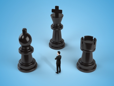 businessman standing among chess pieces isolated in blueの写真素材