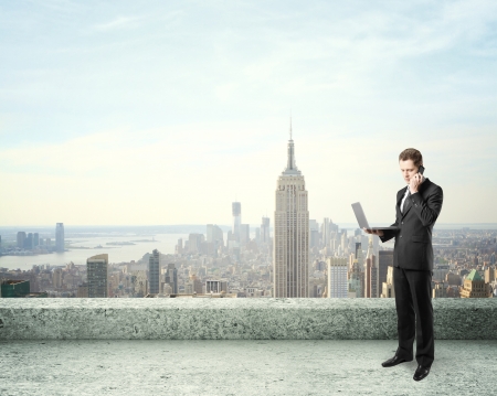 businessman standing on roof and talking on phoneの写真素材