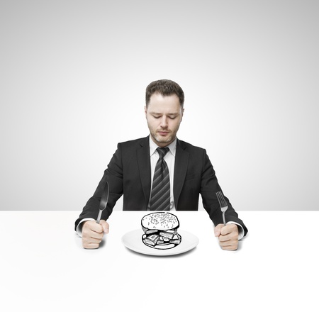 businessman sitting on table and eating hamburger moneyの写真素材