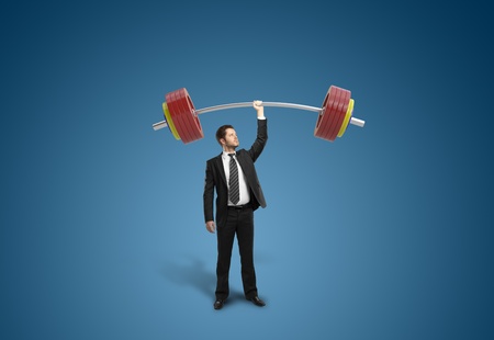 businessman holding barbell on blue backgroundの写真素材