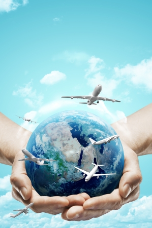 hands holding earth and airplane on sky backgroundの写真素材