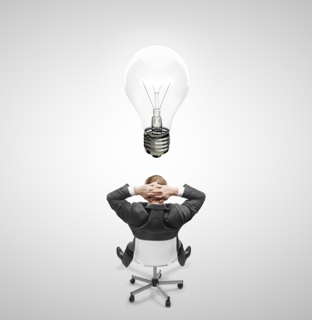 businnessman sitting on chair with lamp over headの写真素材