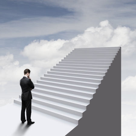 thinking businessman standing near ladder in skyの写真素材