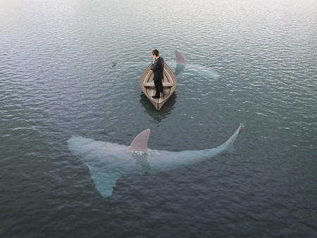 young man thinking  boat with sharks around himの写真素材