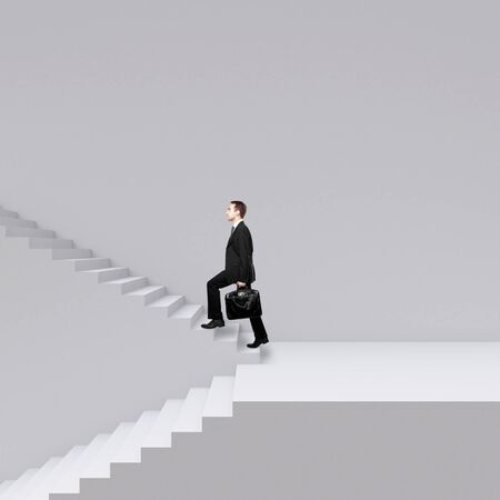 businessman walking on stairs on a gray backgroundの写真素材