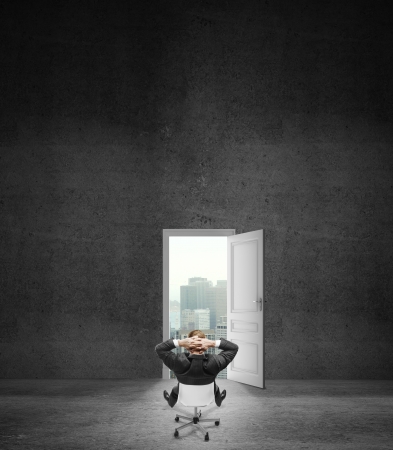 relaxing businnessman sitting on chair and looking at doorの写真素材