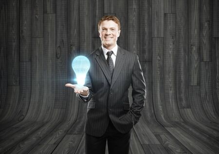 happy businessman holding lightbulb projection in handの写真素材