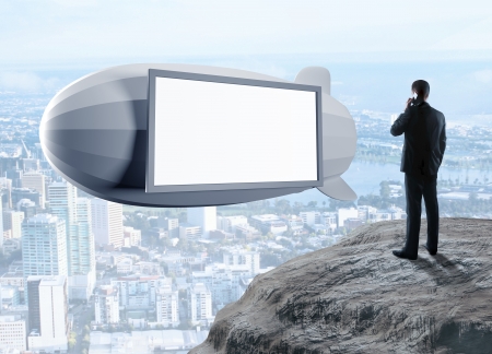 businessman standing on rock and dirigible in skyの写真素材