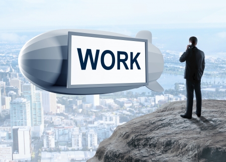 businessman standing on rock and dirigible with work textの写真素材