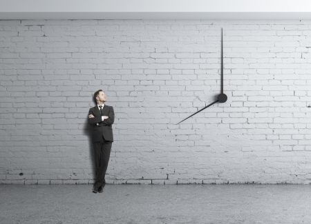 young businessman standing in loft and clock in wallの写真素材