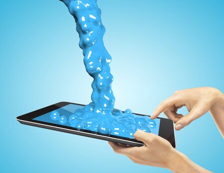 hands holding a tablet with blue splashの写真素材