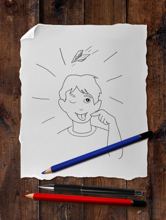 drawing happy boy with tongue on wooden tableの写真素材