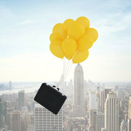 briefcase flying on balloons on city backgroundの写真素材