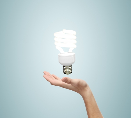 hand and energy saving lamp on a blue backgroundの写真素材