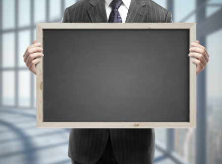 businessman in suit holding blackboard with business concept in officeの写真素材