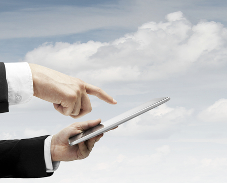 hand holding and pusning touch pad on sky backgroundsの写真素材