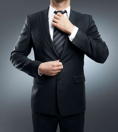 businessman adjusts his tie on gray backgroundの写真素材