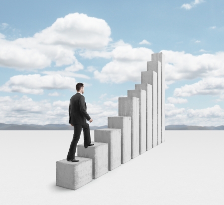 young businessman climbing a graph columnの写真素材