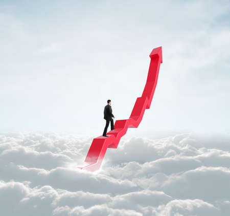 businessman climbing a red arrow in skyの写真素材