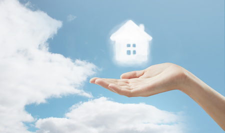 hand holding cloud house on skyの写真素材