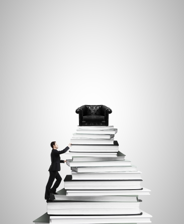 businessman climbing on stack of books with sofaの写真素材