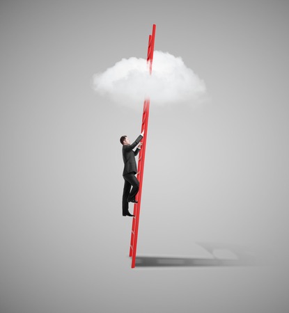 young man standing on ladder and looking to cloudの写真素材