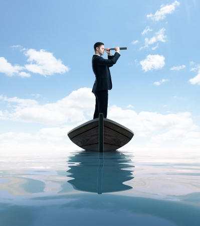 businessman standing on a boat and looking through a telescopeの写真素材
