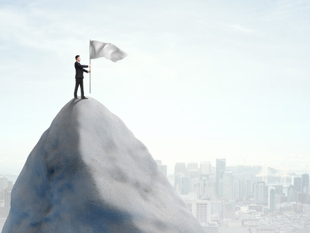 young man standing on top of mountain with flagの写真素材