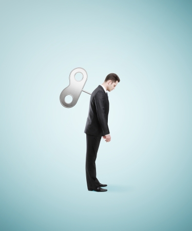 businessman stands without energy with the winder backの写真素材