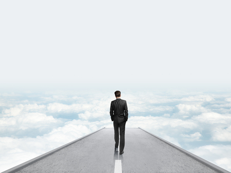 businessman walking on concrete bridge an looking cloudsの写真素材