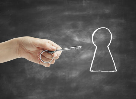 key in hand and drawing keyhole on deskの写真素材