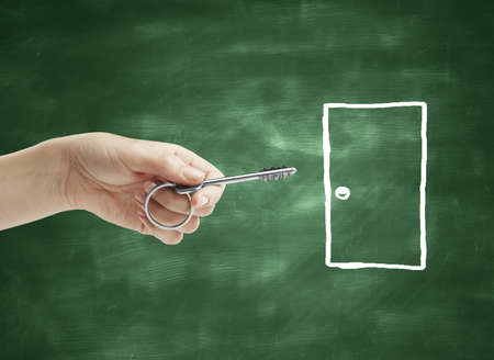 hand holding key and drawing door on deskの写真素材