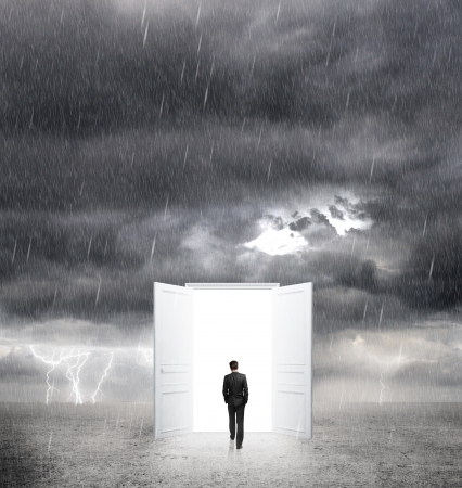 businessman walking to opened door from bad weather to whiteの写真素材