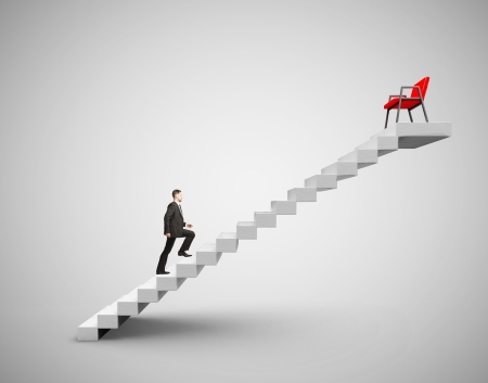 businessman in suit climbing to chairの写真素材