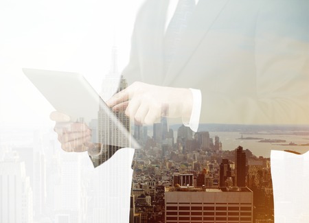 businessman with touchpad standing on city backgroundの写真素材
