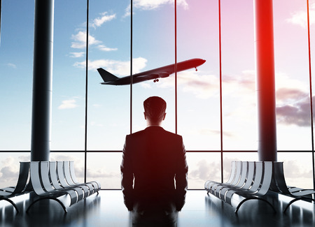 businessman in airport looking to airplane in skyの写真素材