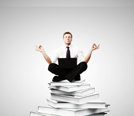 businessman meditation on a pile of booksの写真素材