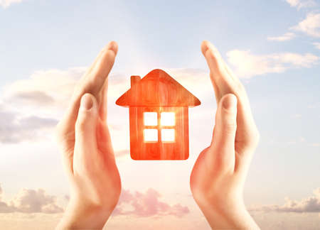 hands holding house on a sky backgroundの写真素材